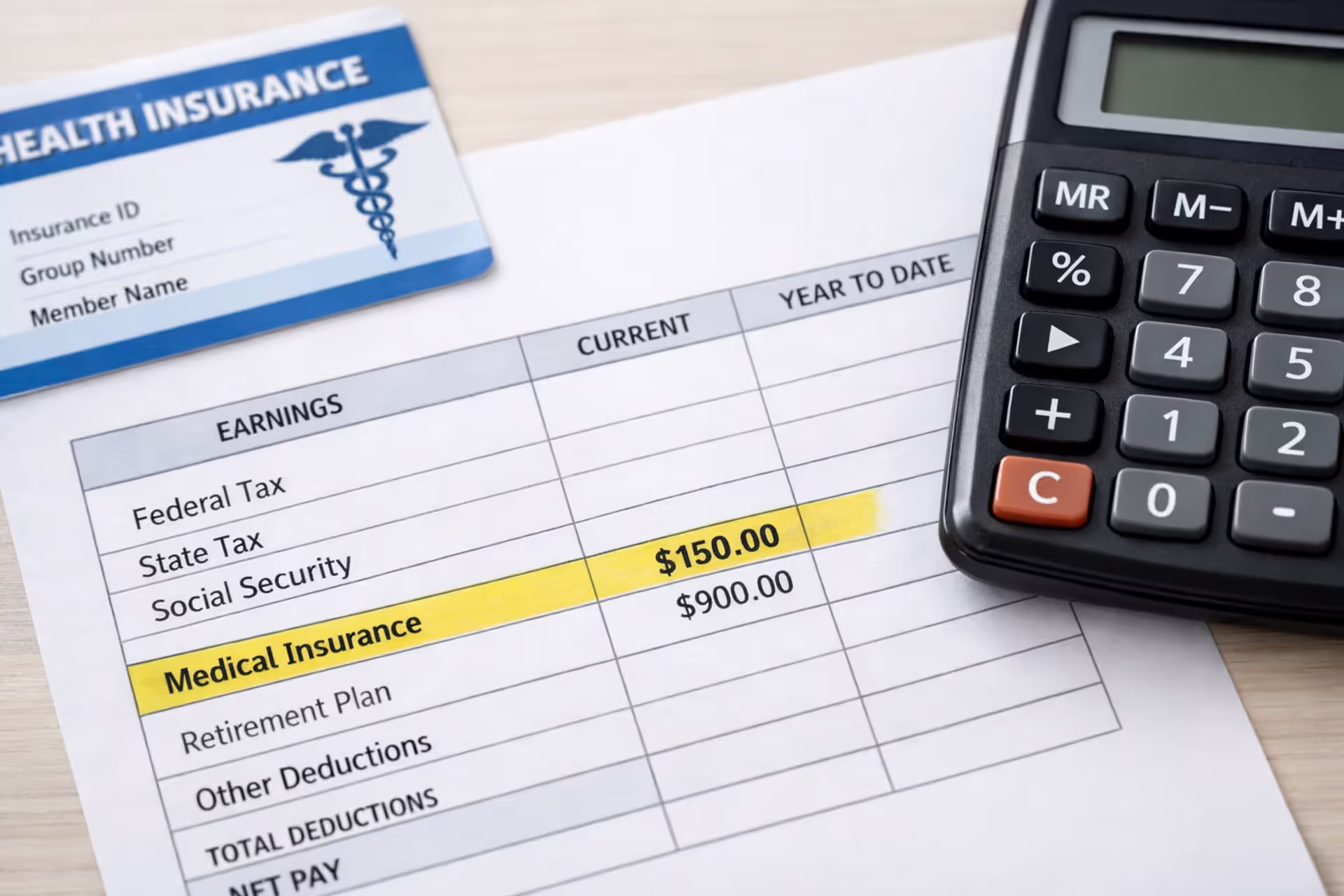 Close-up of a pay stub with highlighted health insurance deduction line next to a health insurance card and calculator on an office desk